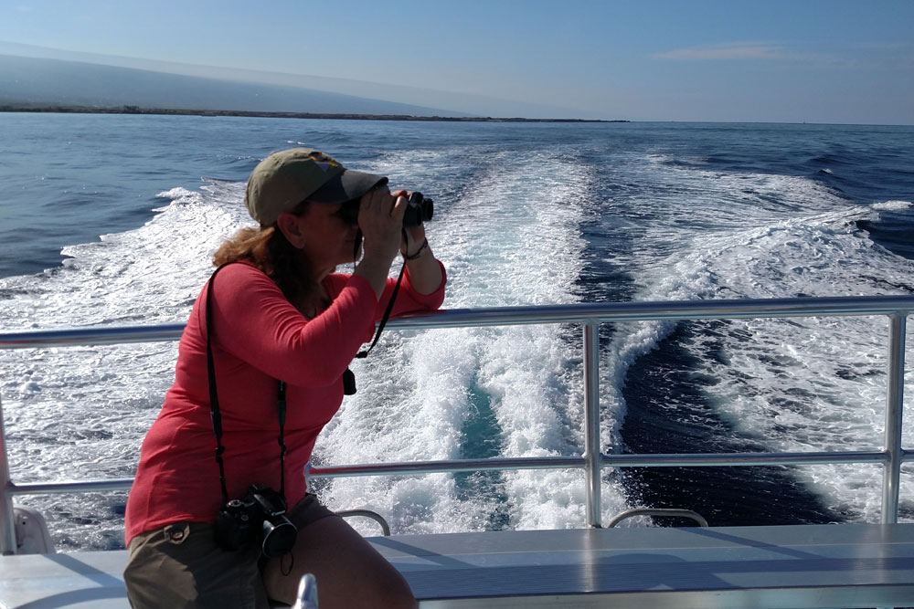 woman on boat looks through binoculars